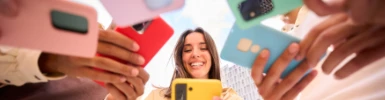 Fröhliches Mädchen schaut auf Smartphone. Gruppe von Freunden mit Handys